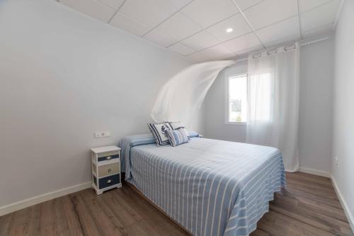 a white bedroom with a bed and a window at Apartamento Constancia in Sant Carles de la Ràpita