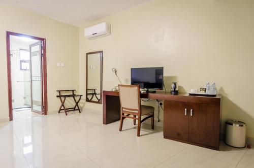 a room with a desk with a television and a chair at Hillside Plaza Hotel in Kampala
