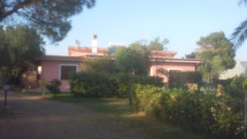 a pink house with trees and bushes in front of it at La Contea in SantʼAnna Arresi