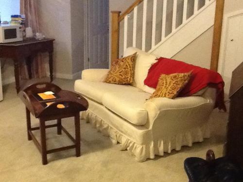 a living room with a white couch with pillows on it at 5 High Street in Temple Combe
