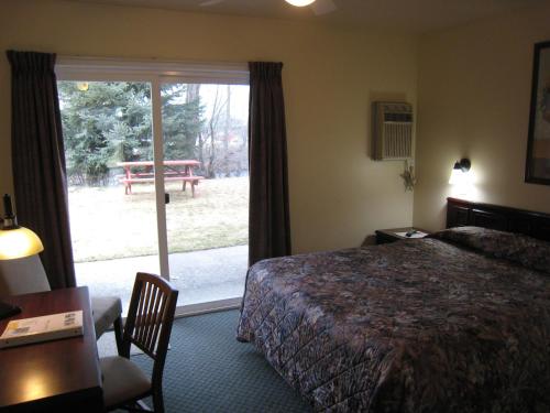 Habitación de hotel con cama y puerta corredera de cristal en Johnny's Motel, en Grand Forks