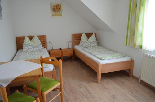 a room with two beds and a table and chairs at Frühstückspension Sterr in Strebersdorf