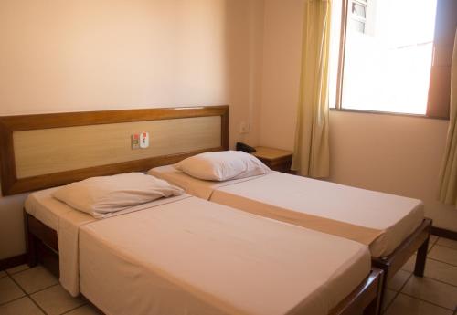 two twin beds in a room with a window at Pousada Raio do Sol in Ilhéus