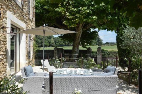 a table and chairs with an umbrella in a yard at Les Gîtes Du Clos D'Olea in Oppède