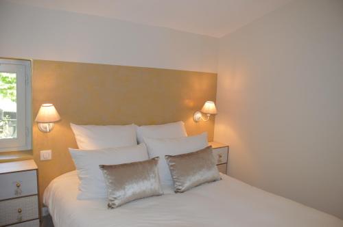 a bedroom with a white bed with two pillows at Les Gîtes Du Clos D'Olea in Oppède