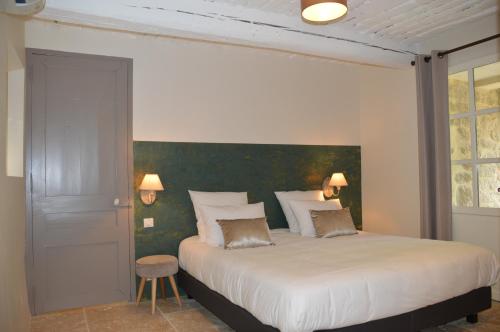 a bedroom with a large bed with a green accent wall at Les Gîtes Du Clos D'Olea in Oppède
