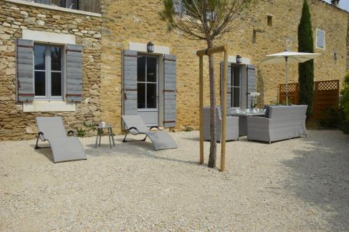 a group of chairs and an umbrella in front of a building at Les Gîtes Du Clos D'Olea in Oppède