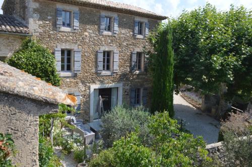 an old stone house with a tree in front of it at Les Gîtes Du Clos D'Olea in Oppède