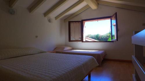 a bedroom with two beds and a window at Lavu Santu in Sainte-Lucie de Porto-Vecchio