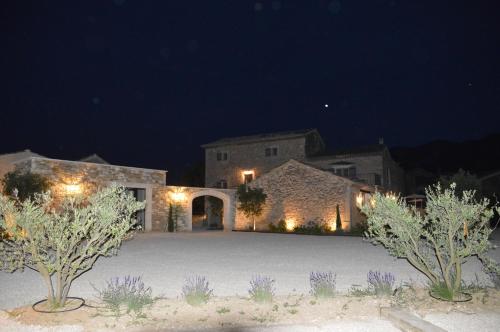 a large stone house with a courtyard at night at Le Clos D'Olea in Oppède