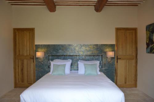 a bedroom with a bed with white sheets and pillows at Le Clos D'Olea in Oppède