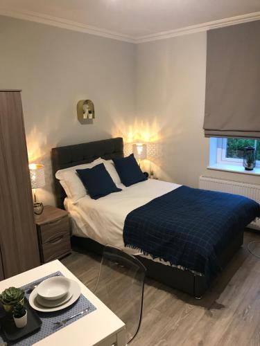 a bedroom with a bed with a blue blanket and a table at Berkshire Apartments 1 Helena House Brownlow Road in Reading