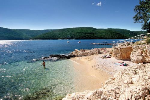 a person standing in the water on a beach at Apartment Štrmac in Labin