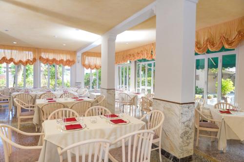 a restaurant with white tables and chairs and windows at Albergo Battelli Only Adults in Marina di Pietrasanta