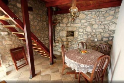 comedor con mesa y pared de piedra en Holiday Home Banalu en Jadranovo