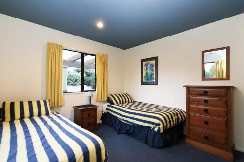 a bedroom with two beds and a dresser and two windows at Rifugio - Lake Tekapo in Lake Tekapo