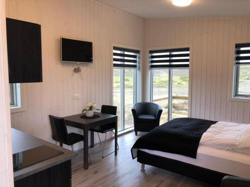 a bedroom with a bed and a table and chairs at Afternoon Cottages in Hella