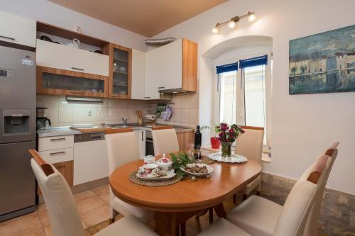 Una cocina con una mesa de madera y gabinetes blancos. en Apartment Pere, en Trogir