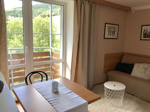 a living room with a table and a large window at Apartmány Gryf Harrachov in Harrachov