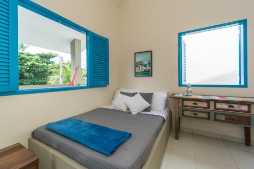 Un dormitorio con una cama y una cómoda y dos ventanas. en Casa Azul Home Stay, en Porto de Galinhas
