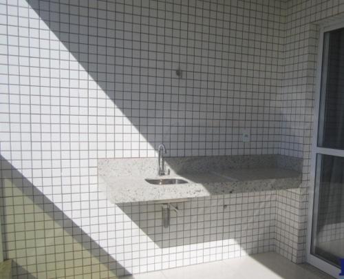 Baño de azulejos blancos con lavabo y bañera en Apartamento a 200 m da Praia do Morro, en Guarapari