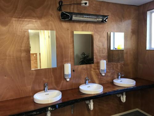a bathroom with three sinks and two mirrors at Tongariro Holiday Park in National Park