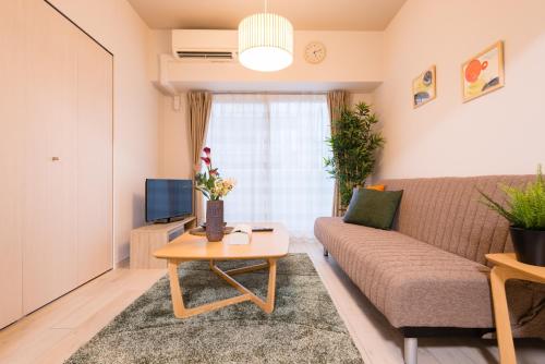 a living room with a couch and a table at nedoco OSAKA SHINSAIBASHI - formerly FORESTAY Shinsaibashi in Osaka
