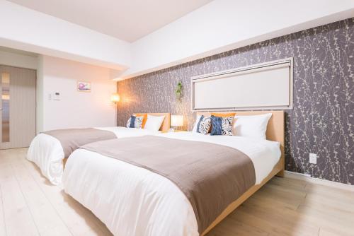 two beds in a hotel room with a wall at nedoco OSAKA SHINSAIBASHI - formerly FORESTAY Shinsaibashi in Osaka