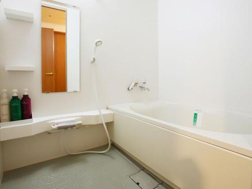 bagno con lavandino e vasca con specchio di APA Hotel Sapporo Susukino Eki Nishi a Sapporo