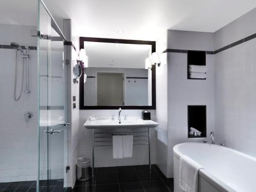 a bathroom with a sink and a tub and a mirror at Amora Hotel Jamison Sydney in Sydney