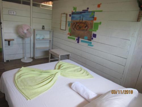 a bedroom with a white bed with a yellow bow on it at Posada Ecoturística El Valle in El Valle