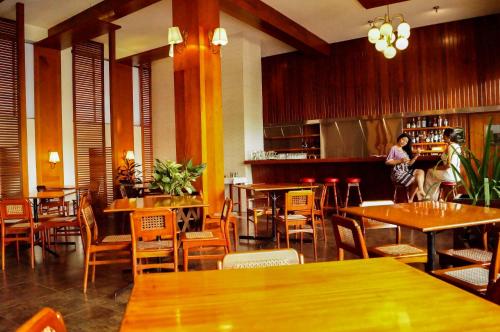 um restaurante com mesas e cadeiras de madeira e um bar em Grand Hotel Mercedes em Pucallpa