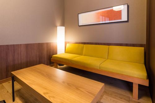 Sofá amarillo en una habitación con mesa en Bijou Suites Musubi, en Osaka