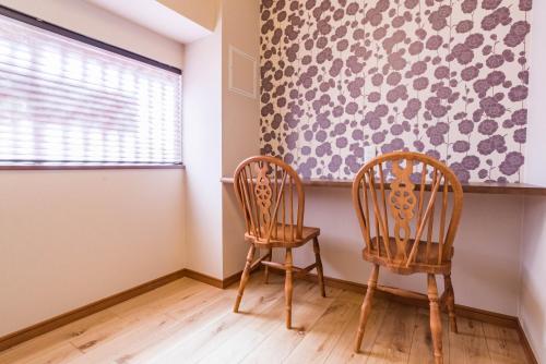 two chairs in a room with a wall at Bijou Suites Musubi in Osaka