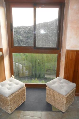 two wicker chairs sitting in front of a window at La Posada del Arba in El Frago