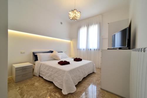 a white bedroom with a bed and a television at Villa Luigia Luxury Relais in Gallipoli