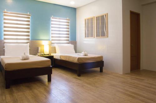 two beds in a room with blue walls and wooden floors at Sheridan Boutique Hotel in Puerto Princesa City