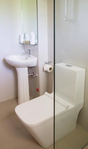 a white bathroom with a toilet and a sink at Sheridan Boutique Hotel in Puerto Princesa City