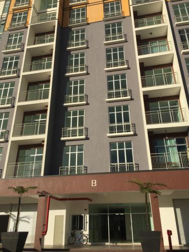 a tall apartment building with palm trees in front of it at Cameron's Square Apartment in Cameron Highlands