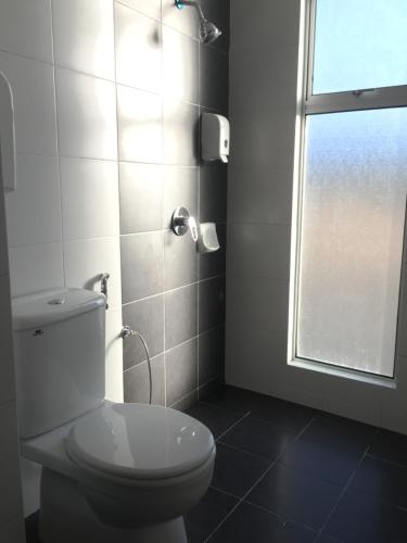 a white bathroom with a toilet and a window at Cameron DreamWorld Apartment @ Golden Hill in Cameron Highlands