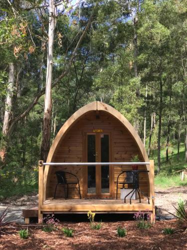 a small wooden cabin with two chairs in the woods at BIG4 Yarra Valley Park Lane Holiday Park in Healesville