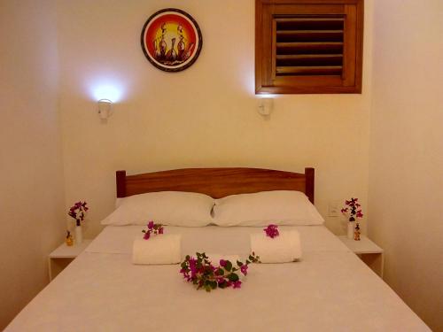 a bed with two white pillows and flowers on it at Guaco House in Jericoacoara