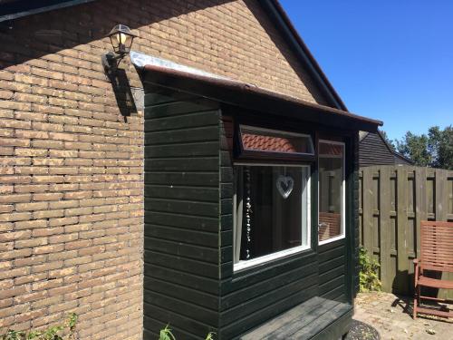 a green shed with a window and a fence at Bungalow Halfweg in Ballum