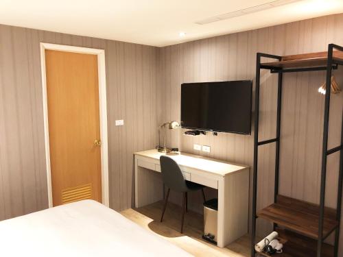 a bedroom with a desk and a tv on a wall at La Hotel-Baseball Theme Hall in Kaohsiung