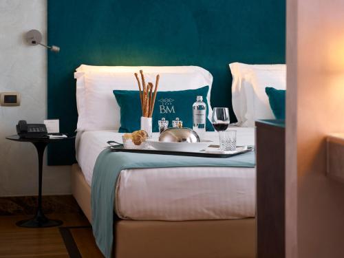 a bed with a tray of food and a glass of wine at Bianca Maria Palace Hotel in Milan