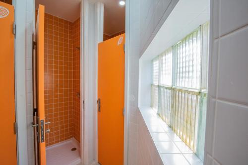 La salle de bains orange est pourvue d'une douche et d'une fenêtre. dans l'établissement VisHostel, à Viseu