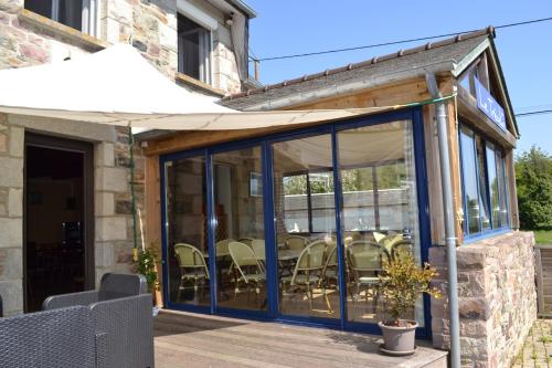 a conservatory with glass doors and chairs on a deck at Hôtel Le Trécelin in Frehel