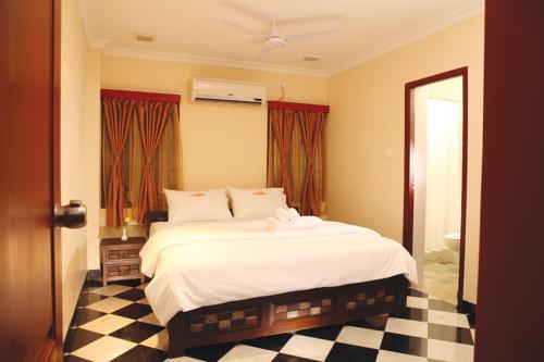 a bedroom with a large bed with a checkered floor at Meenakshi's Sunshine Hotel in Madurai