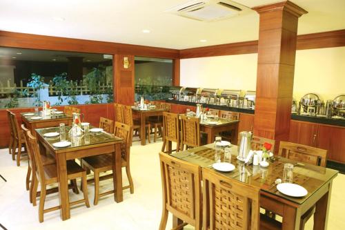 a restaurant with wooden tables and chairs and a bar at Meenakshi's Sunshine Hotel in Madurai