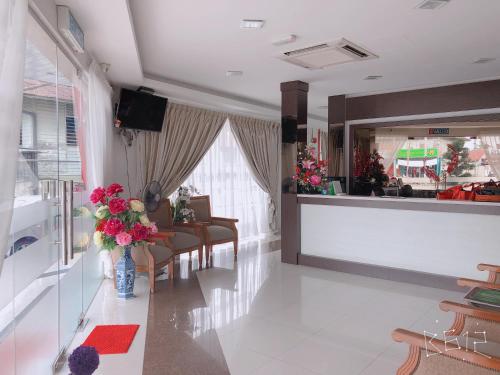 un salón con una sala de espera con flores en un mostrador en G Star Hotel, en Pantai Remis